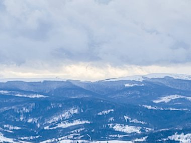 Karlı bir dağda snowboard yapan bir adam.