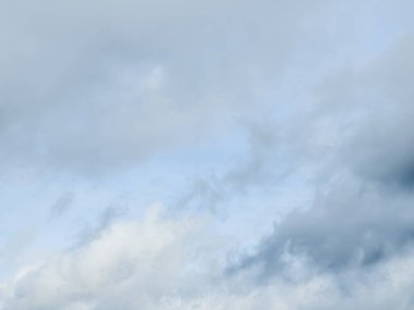 Bulutlu bir arka planı olan gökyüzünde uçan bir uçak.