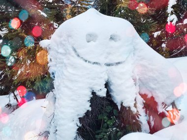 Arka planda Noel ağacı olan kardan bir adam.