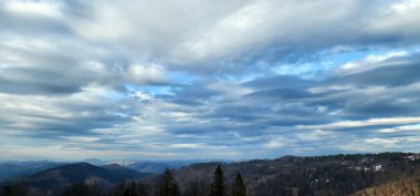 Dağları ve bulutlu gökyüzü olan güzel bir manzara.