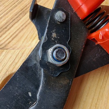 Canlı kırmızı saplı siyah bir bahçe budama makinesi kullanıma hazır, işlevselliği bir renk patlaması ile harmanlıyor. Bu kullanışlı araç kolay ve stil ile bahçıvanlık görevleri ele almak için hazırlanmış.