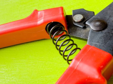 Canlı kırmızı saplı siyah bir bahçe budama makinesi kullanıma hazır, işlevselliği bir renk patlaması ile harmanlıyor. Bu kullanışlı araç kolay ve stil ile bahçıvanlık görevleri ele almak için hazırlanmış.