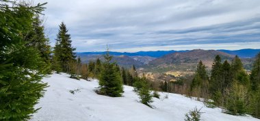 Bulutlu gökyüzünün altında karlı bir dağ sırasının güzel bir görüntüsü.