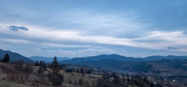 Mavi gökyüzünün arka planındaki güzel dağ ve köy manzarası. Karpat Dağları