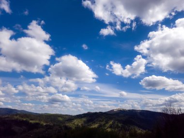 Bulutlu ve mavi gökyüzü olan dağ manzarası.
