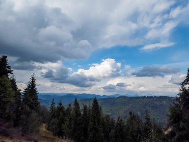 Dağlarda güzel bir manzara. Önünde bulutlu mavi bir gökyüzü var..