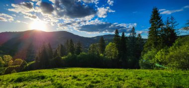 Arkasında mavi gökyüzü olan dağlarda gün batımı