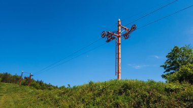Mavi gökyüzünün arka planında elektrik direği ve kablolar