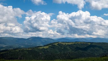 Yeşil ağaçları ve mavi gökyüzü olan dağ sırası