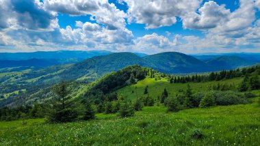 Arka planda mavi gökyüzü olan yeşil dağlar.