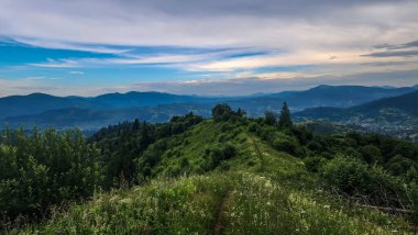 Bulutlu gökyüzü ile dağlık bir bölgenin güzel bir görüntüsü.