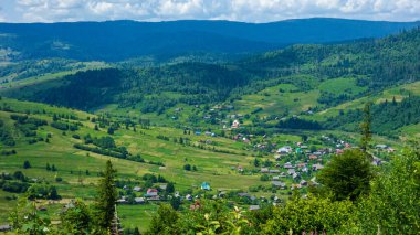 Köyü olan yeşil tepelere bak.