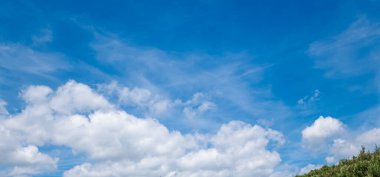 Bulutlu ve yeşil yapraklı mavi gökyüzü.