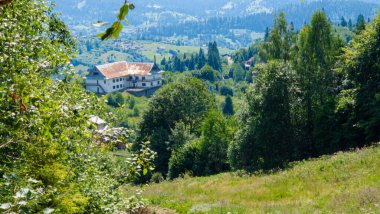 Güneşli havada dağlarla, ağaçlarla ve ormanlarla dolu güzel bir yaz manzarası.