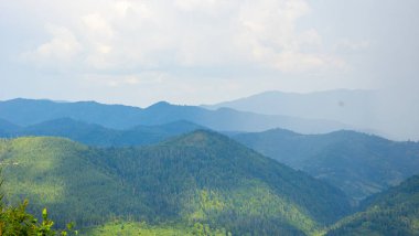 Dağları ve bulutlu gökyüzü olan güzel bir manzara.