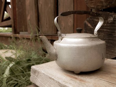 Ahşap evin duvarında eski metal çaydanlık var.