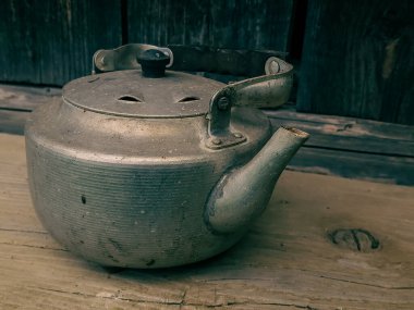 Ahşap arka planda kapağı olan eski tip bir çaydanlık.