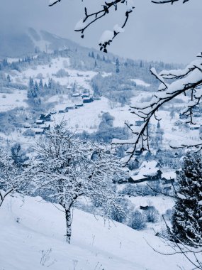 Karla kaplı kış dağı manzarası ve dağlarda küçük bir ahşap köy..