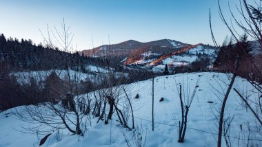 Akşam ışığında karla kaplı dağ sıraları