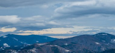 Arka planda mavi gökyüzü ve bulutlu bir dağın tepesinden manzara.