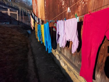 Çamaşır ipinde asılı kırmızı ve mavi elbiselerin yakın çekimi.