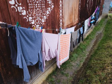 Evin bahçesindeki duvarda çamaşır için kıyafetler var. Elbiseler bahçede kuruyor.