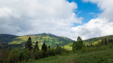 Yazın mavi gökyüzü ve bulutlarla kaplı dağ manzarası