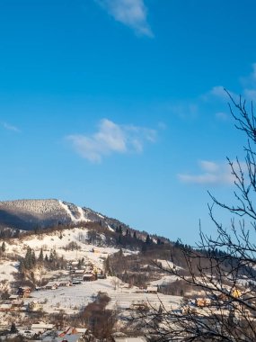 Kışın karla kaplı ağaçlar ve mavi gökyüzü olan dağ manzarası