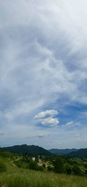 Dağları ve bulutlu gökyüzü olan güzel bir manzara.