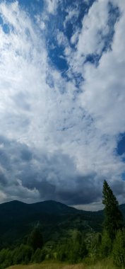 Dağları ve bulutlu gökyüzü olan güzel bir manzara.