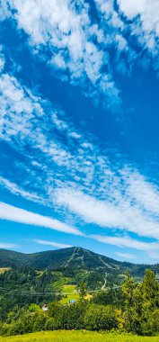 yeşil alanlar ve arkadaki bulutlarla mavi gökyüzü