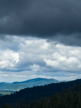 Bulutlu bir günün tepesinden güzel bir manzara. Gökyüzündeki bulutlar. Dağlar ormanlarla ve ormanlarla çevrili.