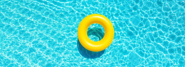 Yellow swimming pool ring float in blue pool water. Summer and vacation concept