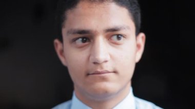 close up shot of a man in a blue shirt making silly eyes movement, funny faces in black background. 4K footage.