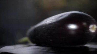 Cinematic close-up shot of fresh eggplant on a black wooden surface. 4K footage.