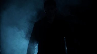 Dramatik bir ışıkta omzuna silah dayayan bir adamın yakın plan çekimi..