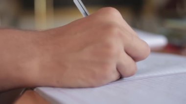 Shot of Human hand writing on a piece of paper with a black colored pen, Hd footage.