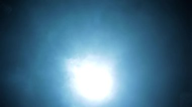 Shot of a man in a long coat and red t-shirt with a pistol in his hand, coming from darkness and shooting. HD footage. Cinematic light with some fog.