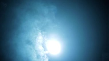 Shot of a man in a long coat and red t-shirt with a pistol in his hand, coming from darkness and shooting. HD footage. Cinematic light with some fog.