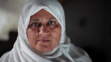 Beyaz tesettürlü Müslüman bir kadın siyah telefon kullanıyor ve gülümsüyor. Müslüman kadın teknolojiyi kullanıyor.
