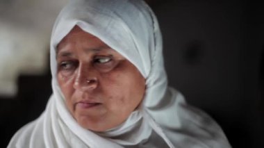 Beyaz tesettürlü mutlu bir müslüman kadının yandan görünüşü. Kameranın önünde gülümseyen tesettürlü Müslüman kadın..