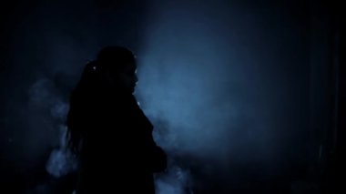 Shot of a female gangster with a gun shooting in the dark, a Cinematic shot with smoke and dramatic light. HD footage. 24 FPS.