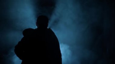 Karanlıkta silahlı bir kadın gangsterin vurulması, dumanlı ve dramatik bir görüntü. Yüksek çözünürlük. 24 FPS.
