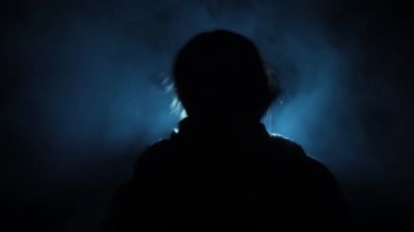 Bir rehinenin, karanlık bir ortamda otururken, bir sandalyeye bağlanmış, dumanlı, yaratıcı ışıklarla çekilmiş yakın plan çekimleri. Yüksek çözünürlük. Kullanımı kolay.