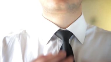 Bir iş adamının kravatını düzeltirken, işyerinde kravatını gevşetirken yakın plan çekimi. Adam kravatını düzeltmekten yoruldu..