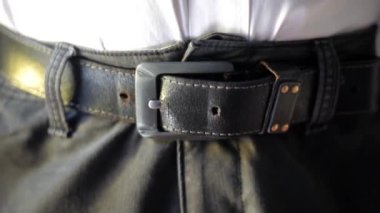 Yorgun ve yorgun bir adam belini çıkarmaktan yoruldu. Kemerini çözen ya da çözen tanınmamış bir adam. Beyaz gömlekli bir adam kemerini çıkarıyor. HD görüntüler.