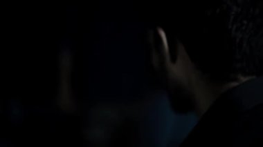 Bilinmeyen bir adamın sandalyeye bağlanmış bir rehineye vurduğu yakın çekim, karanlık yaratıcı ışık. Hd görüntüleri.