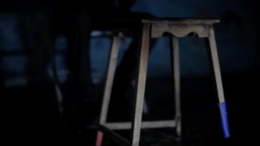Karanlık bir odada tabureyi tekmeleyip yırtık elbiseli tutuklu bir adam HD 'de 24 fps görüntü..
