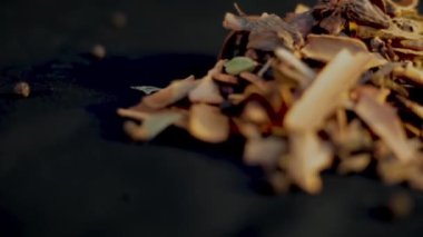 Siyah bir yüzey üzerinde en çok kullanılan ham Hint baharatlarının yakın plan çekimi, kakule, tarçın çubuğu, karabiber, yıldız anason, karanfil, vb..