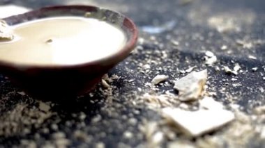 Multani mitti ya da Fuller 'in toprağının siyah bir yüzey üzerindeki yakın çekim görüntüsü ve yüz maskeleri ve doğal olarak parlayan cilt için yüz maskeleri olarak kullanılan çamur bir kaseye yapıştırılması. 24FPS 'te HD görüntüler.
